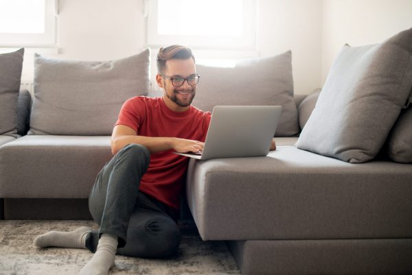 Casually dressed guy is working from home on a laptop.